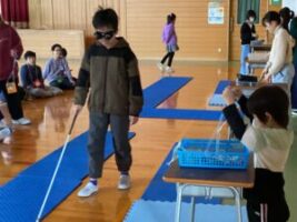 白杖を使って歩行体験をする藤ノ木小学校の児童とゴールでメダルを渡す本校児童